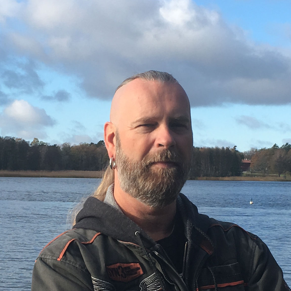The founder of DNSmonitor, Henrik Dahlberg, stands in front of a lake in a close-up photo.