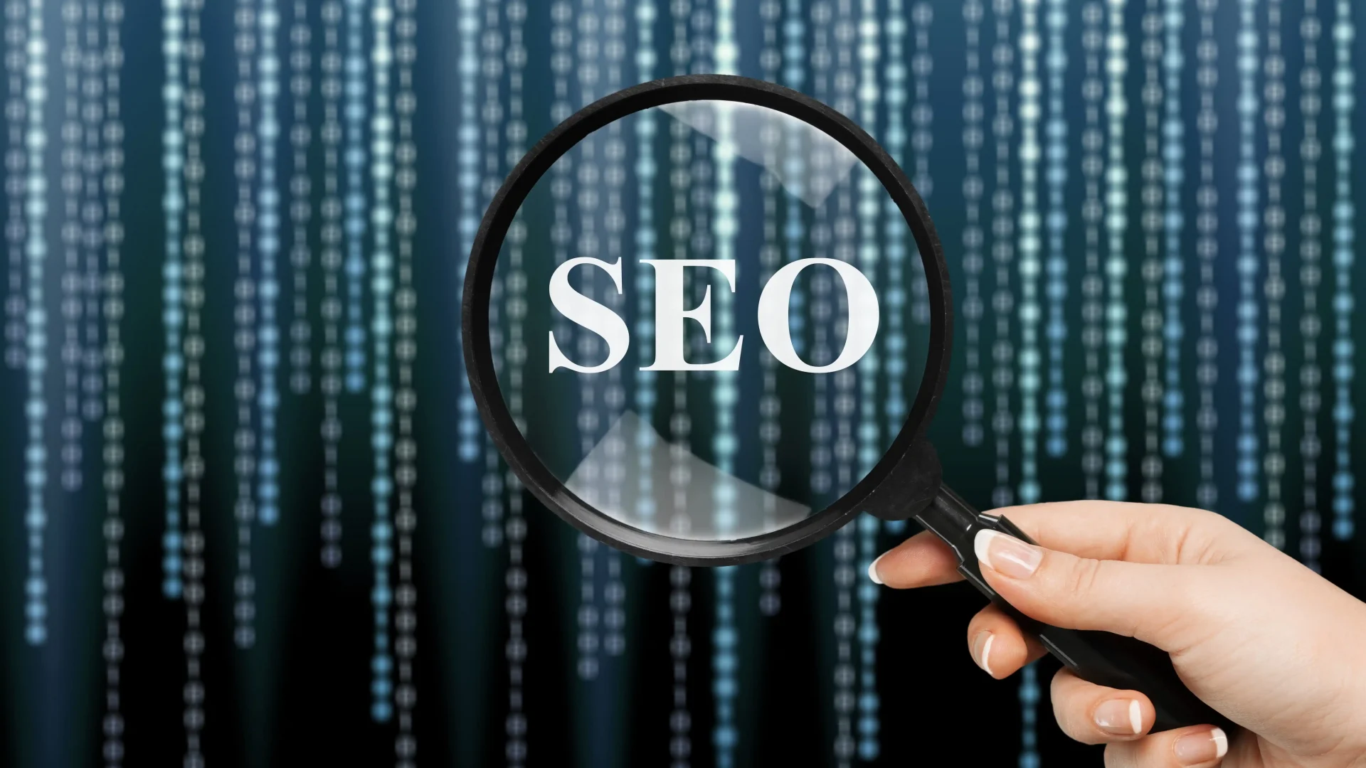 Magnifying glass highlighting “SEO” over digital data background, symbolizing analysis of performance and visibility in search systems.